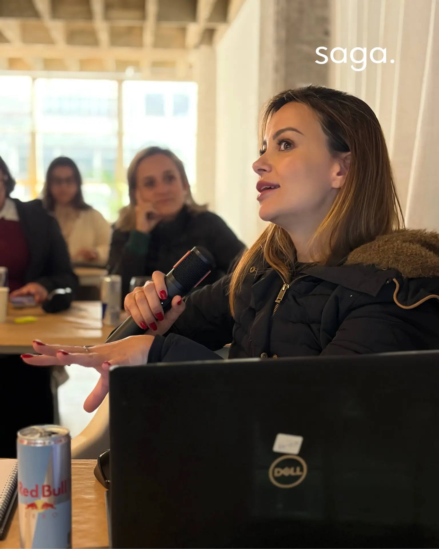 Participante com microfone em mãos apresentando um ponto de vista durante discussão em sala